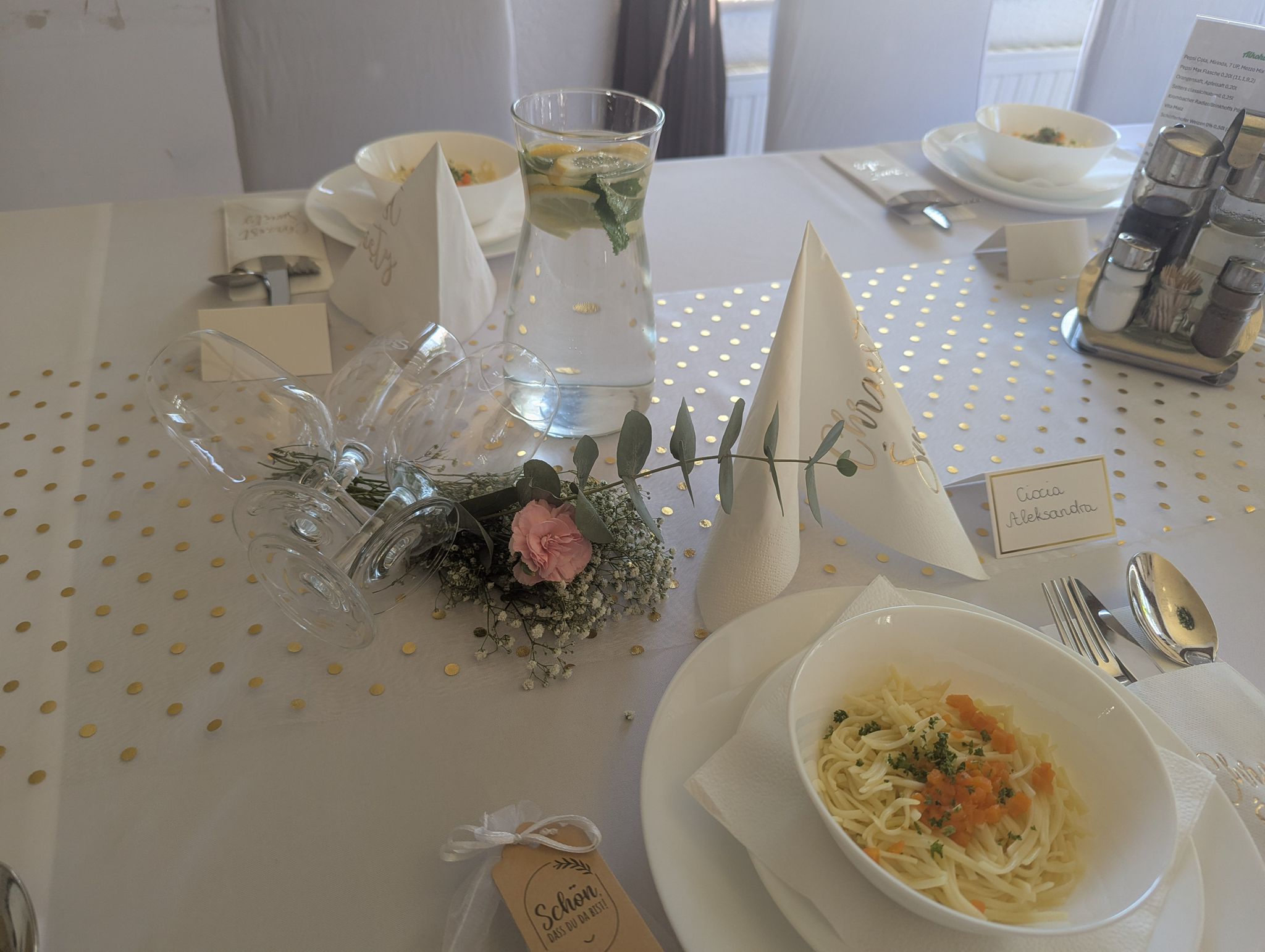 Festlich gedeckter Tisch mit Suppentellern, Blumen und Namenskarten auf weißer Tischdecke